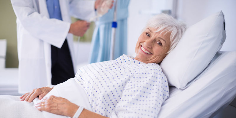 a old woman lying on a hospital bed with a smiling face