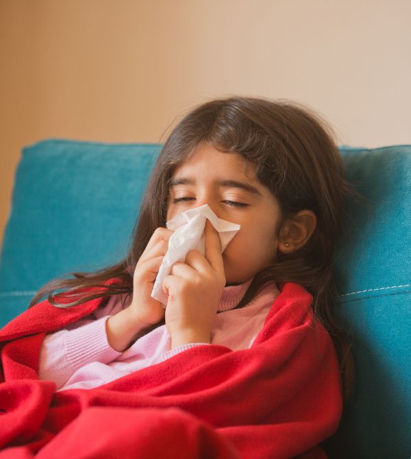 Sick child holding tissue to nose
