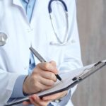 Healthcare professional doctor writing medical records on a clipboard. Female unrecognizable physician at work.