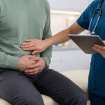 Doctor examines male patient complaining of abdominal pain in a urgent care clinic.
