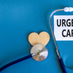 Urgent care on beautiful white card. Wooden heart and stethoscope.