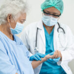 Doctor help elderly old woman patient wearing a face mask in hospital for protect safety infection.