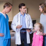 Doctors discussing medical report with mother and daughter in urgent care clinic