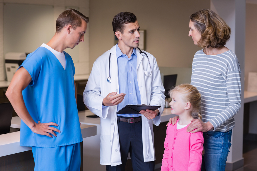 Doctors discussing medical report with mother and daughter in urgent care clinic